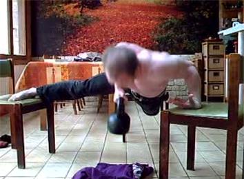 Most Consecutive One-Armed Back-Of-Hand Push-Ups On Three Chairs While Carrying A 20-Kilogram Kettlebell