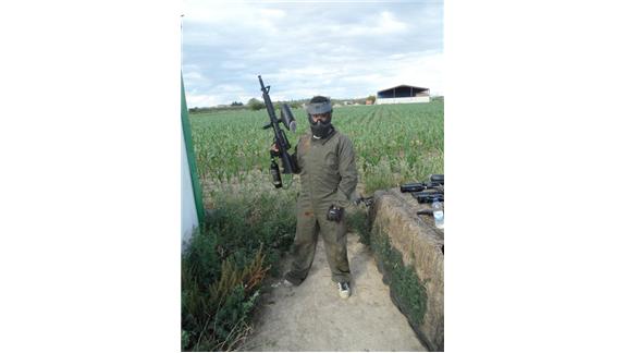 Largest Paintball Gun Holded On Right Hand While Wearing A Green Used Paintball Suit And Mask