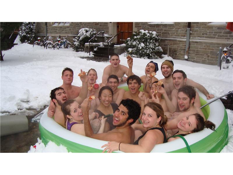 Most College Students In An Inflatable Pool Eating Pizza With Snow On The Ground